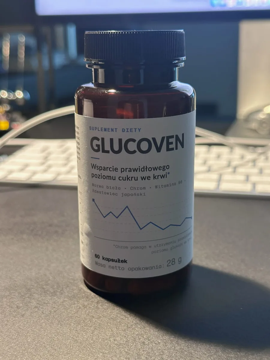 Butelka Glucoven na biurku, w tle rozmyty monitor komputera i klawiatura