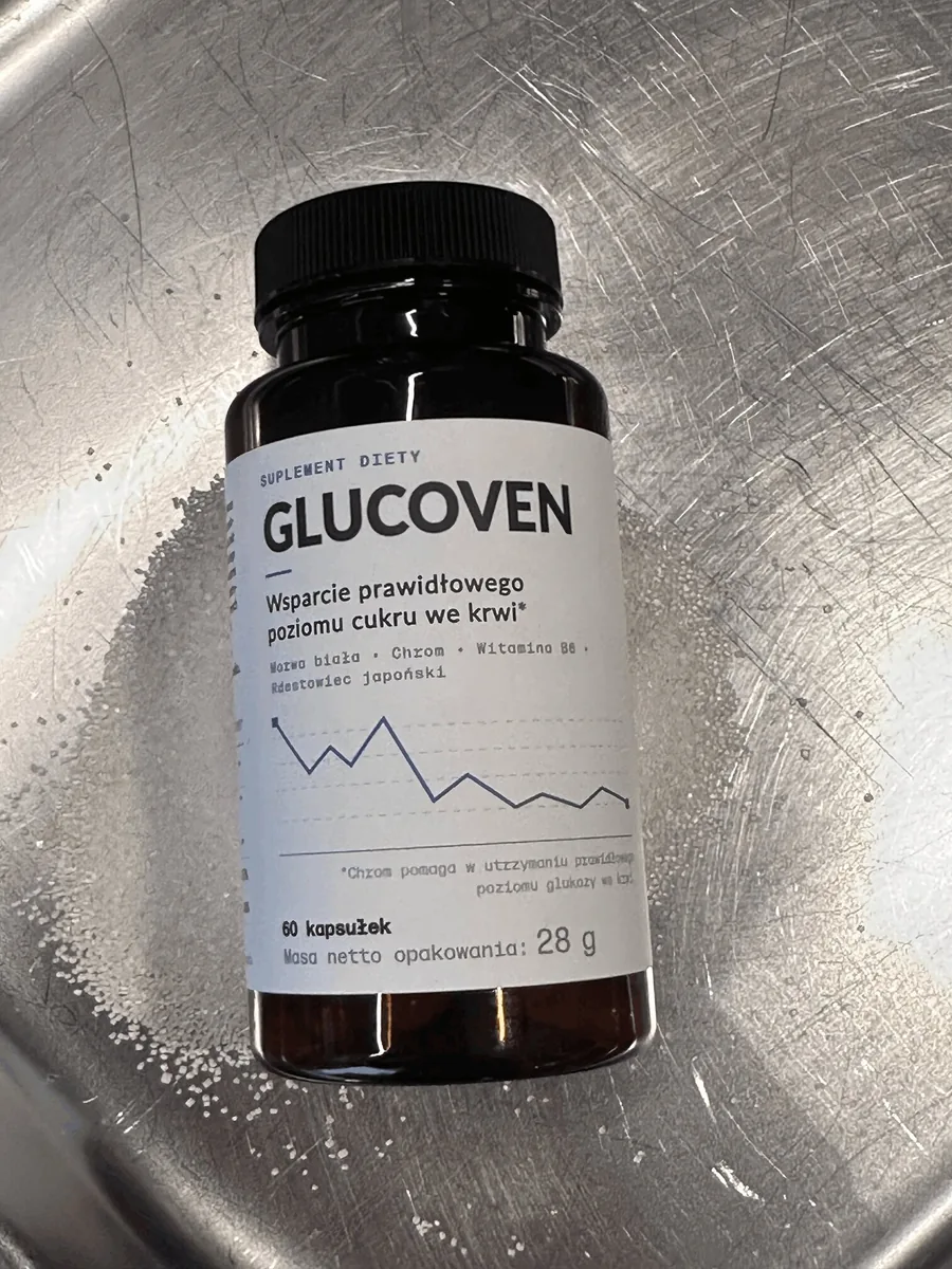 Butelka suplementu Glucoven na porysowanym stalowym blacie z cukrem, szersze ujęcie